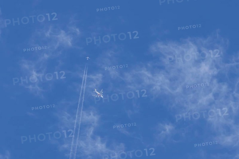 Two airliners Airbus A380 jet passenger aircraft of Emirates airlines and a Boeing 737 of Norweign Air flying in a blue sky, England, United Kingdom