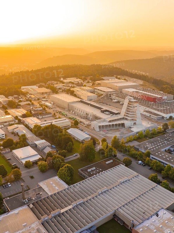 Industrial complex at sunset surrounded by hills and forests, industrial area Wolfsberg Nagold, district Calw, Black Forest, Germany