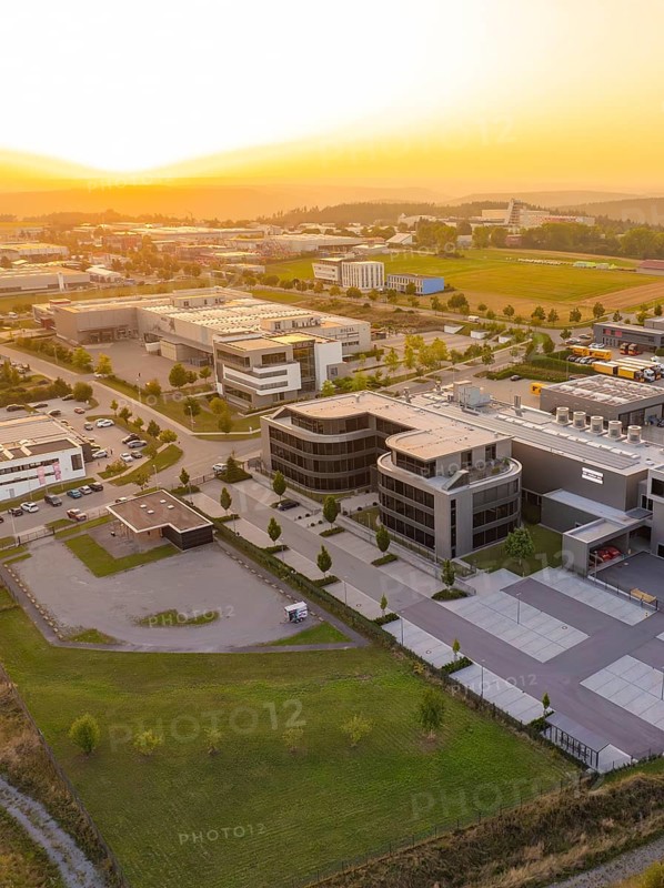 Modern commercial building with car park in a rural setting at sunset, industrial area Wolfsberg Nagold, district of Calw, Black Forest, Germany