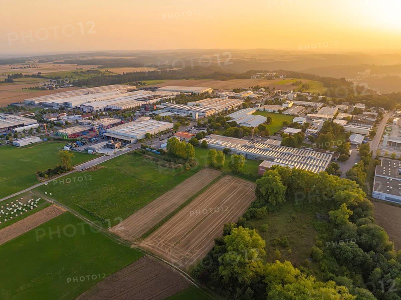 Industrial warehouses and fields in a vast rural landscape at sunset, Wolfsberg Nagold industrial area, Calw district, Black Forest, Germany