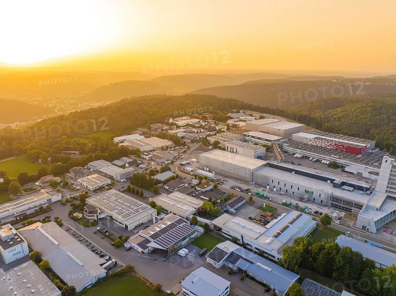 Large industrial complex at sunset, embedded in a hilly landscape with forests, industrial area Wolfsberg Nagold, district Calw, Black Forest, Germany