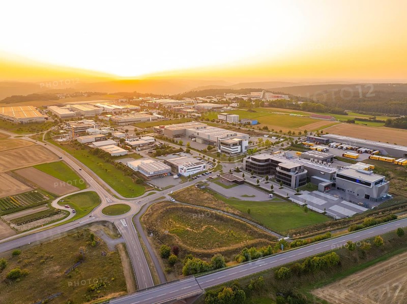 Wide view of an industrial area at sunset, surrounded by fields and forests, industrial area Wolfsberg Nagold, district Calw, Black Forest, Germany