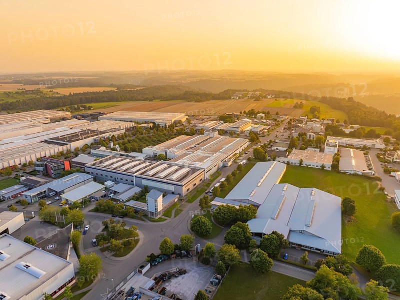 Industrial plants next to fields and forests in the warm light of the sunset, industrial area Wolfsberg Nagold, district Calw, Black Forest, Germany