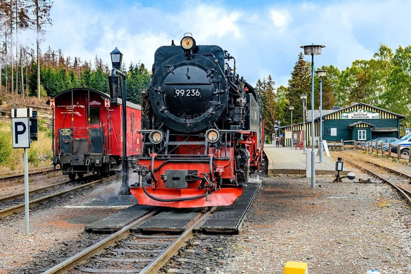 View of middle steam locomotive steam locomotive of Harz narrow-gauge railway narrow-gauge railway Brockenbahn stands on track towards summit of Brocken on right platform of Schierke station, left end of train with iron wagon passenger wagon of downhill train, Schierke, Wernigerode im Harz, Saxony-Anhalt, Germany