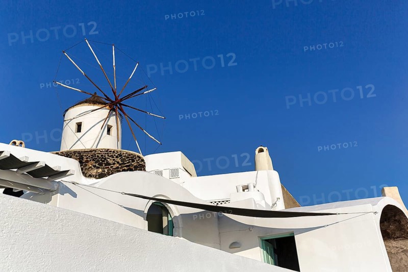 White windmill, typical holiday home, blue sky, sunny weather, text free space, Oia, Thira, Santorini, Cyclades, Greece