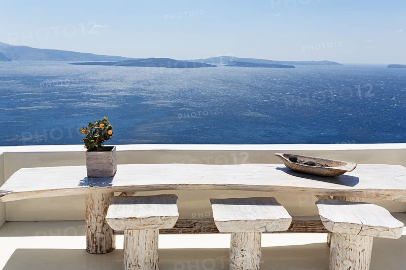 Wooden table on a white terrace by the sea, view of the caldera, Oia, Thira, Santorini, Cyclades, Greece