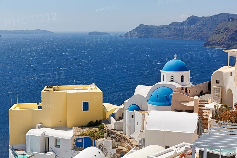 Yellow holiday home by the sea, with typical roof terrace, orthodox church with blue dome, view into the caldera, Oia, Thira, Santorini, Cyclades, Greece