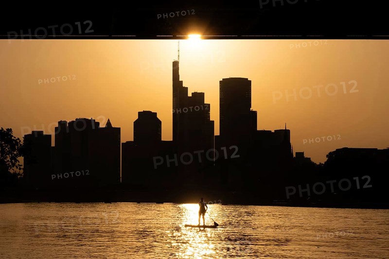 The evening sun stands over the Frankfurt banking skyline while paddlers and rowers navigate the Main, Frankfurt am Main, Hesse, Germany