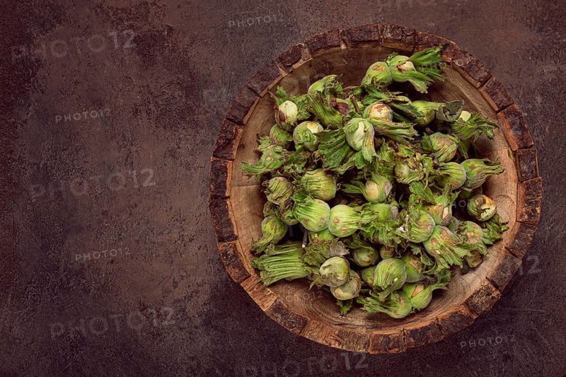 Fresh, green hazelnuts, close-up, in a wooden bowl, unpeeled, top view, no people