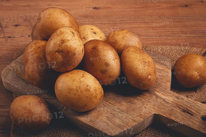 Raw potatoes, scattered on a chopping board, close-up, no people