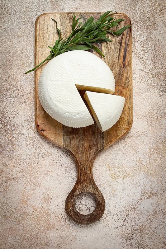 Head of Georgian cheese, Imereti variety, top view, on a cutting board