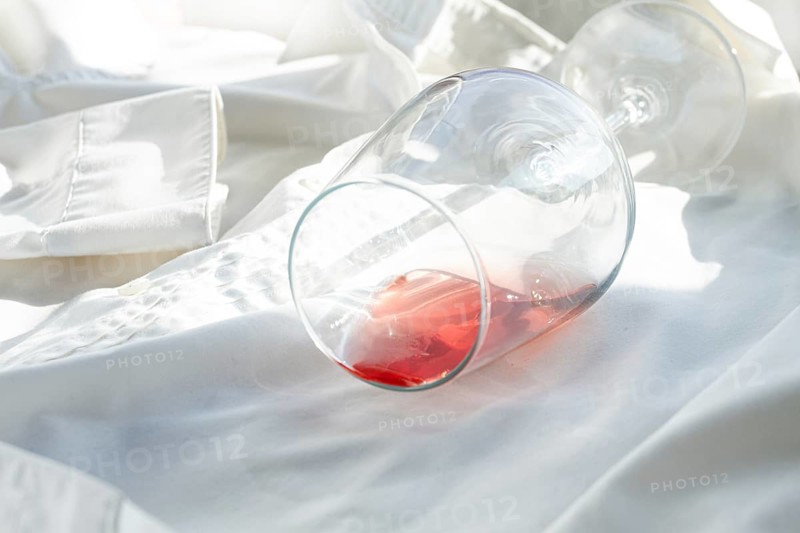 Glass, with pink wine, spilled on a white shirt, close-up, selective focus, no people, concept, top view