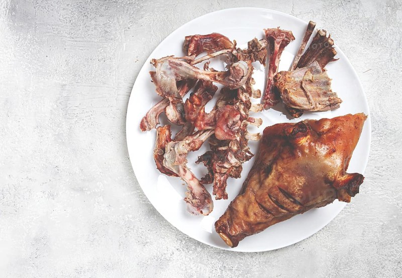 Roast pork head, with remnants of bones and meat, on a white platter, no people, close-up