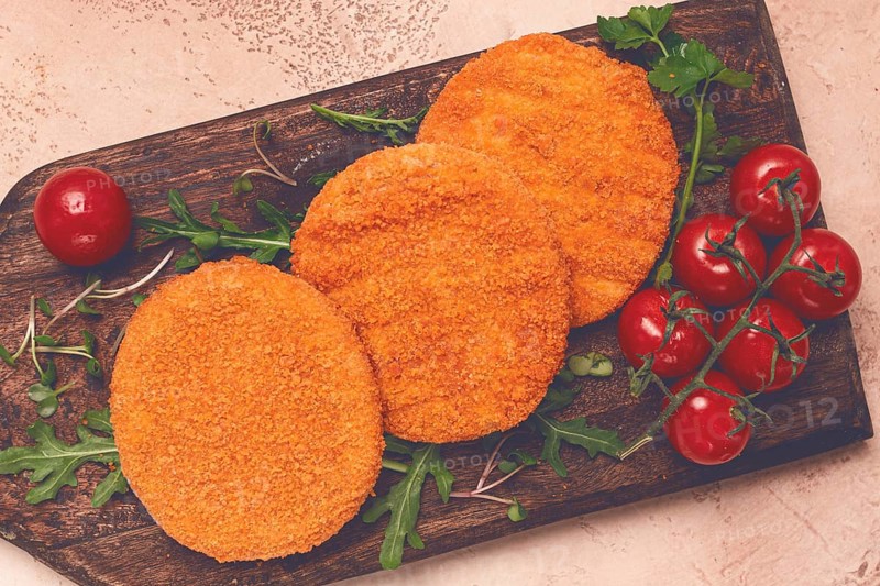 Crispy fried fish cutlets, fish burgers, on a wooden chopping board, with arugula and cherry tomatoes, homemade, no people