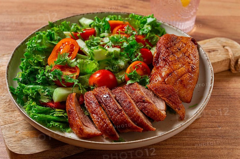 Delicious grilled duck breast served with fresh garden salad and cherry tomatoes at a rustic dining table