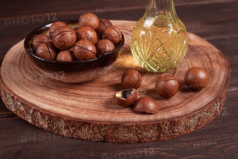 Bottle of macadamia oil, on a wooden board, with macadamia nuts, wooden background, selective focus, no people