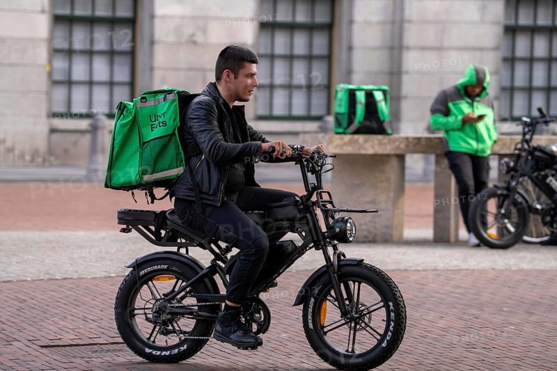 Bicycle traffic in Groningen, Uber Eats, courier driver with e-bike in moped style, fatbike, Netherlands