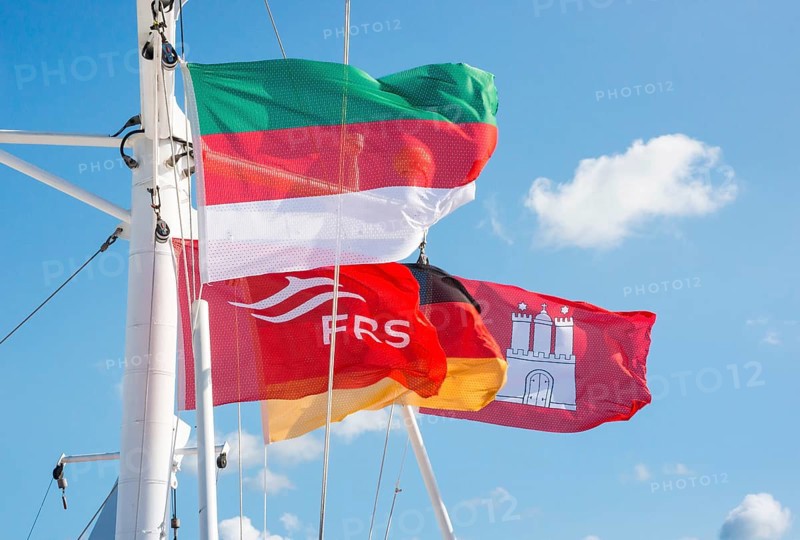 Flag of Heligoland, flag of the shipping company FRS, German flag and Hamburg state flag, flags, flags in vivid colours waving in the wind, hung on the mast of the ferry Halunderjet from Hamburg to Heligoland, catamaran, high speed, high speed, speedboat, boat trip, shipping, clear sky with small white clouds, holiday, sea, maritime, excursion, day trip, day trip, trip with the Halunderjet from Hamburg to Heligoland, Elbe, Lower Saxony, Schleswig-Holstein, Germany
