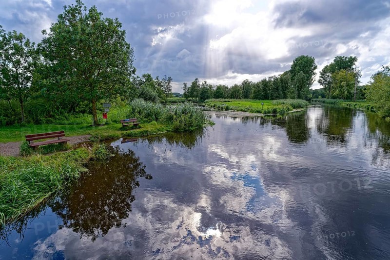 Sun and clouds over the River Trave at a resting place in Brenner Moor. The Brenner Moor is a salt moor, FFH area, in the Trave lowlands near Bad Oldesloe. Schleswig-Holstein, Germany