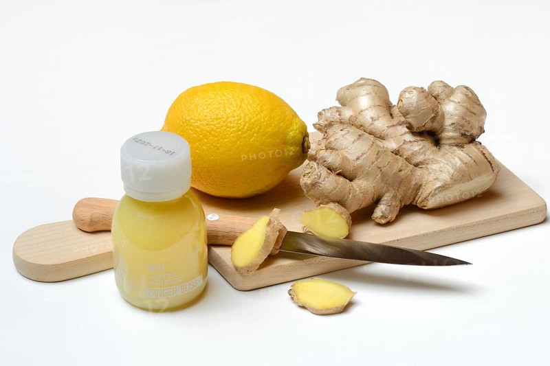 Ginger root and lemon on cutting board and ginger shot