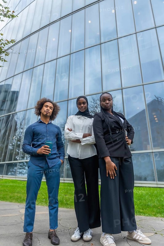 Young diverse business team standing together with confidence outdoors, reflecting professionalism, ambition, and collaboration in a contemporary urban environment