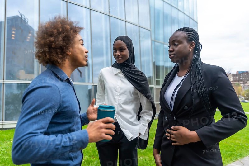 Diverse business professionals standing outdoors, engaging in an informal discussion during a break, demonstrating collaboration and teamwork in a modern urban environment