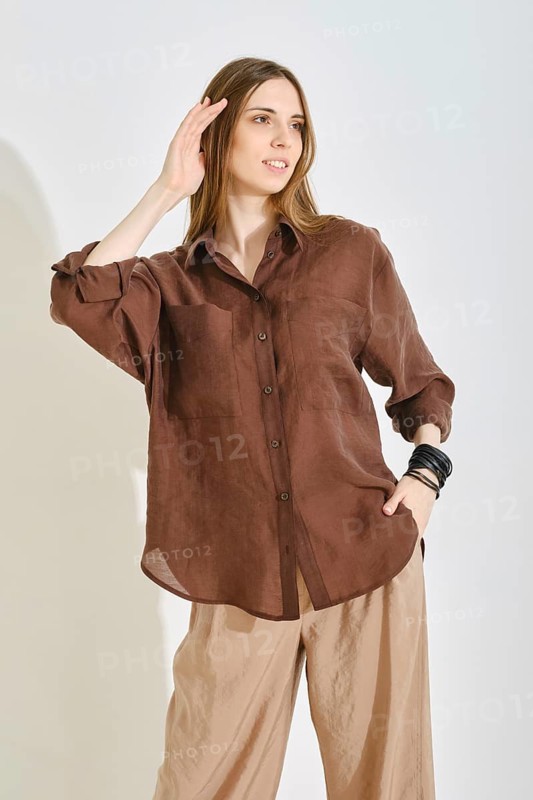 A woman showcases a stylish outfit with a brown button-up shirt and light beige pants, perfect for a casual afternoon
