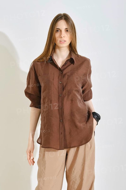 A woman in a stylish brown shirt paired with light pants, highlighting a trendy outfit suitable for various occasions. The focus is on comfort and practicality in her ensemble
