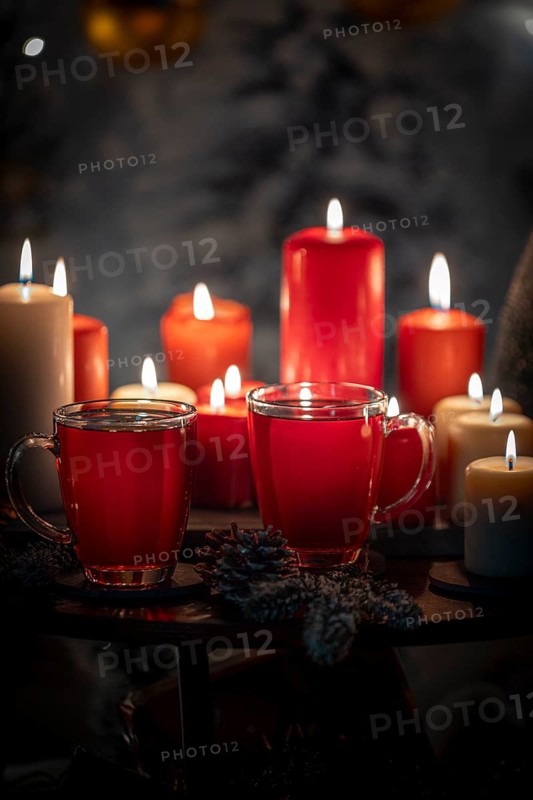 Close-up of red and white candles with tea in cups, Christmas background