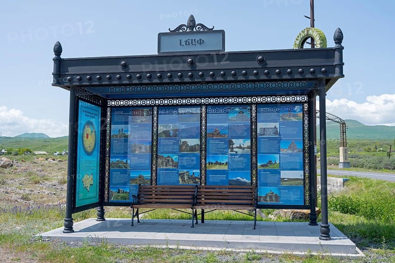 Bus stop with information posters surrounded by rural landscape under blue sky, bus stop at Lake Sevan, Gegharkunik Province, Armenia