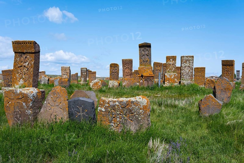 Numerous ancient tombstones on a lush green meadow under a clear blue sky, crossstones, khachkars, the world's largest khachkar field, Noratus cemetery, Noradus, Gegharkunik province, Armenia
