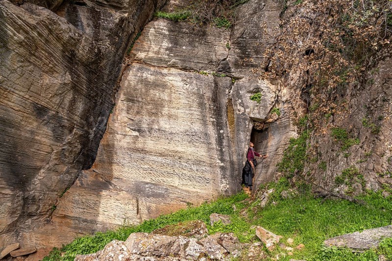Tourist in the quarry near the prehistoric Palli-Lakka dragon houses Drakospita near Styra, island of Euboea or Evia, Greece