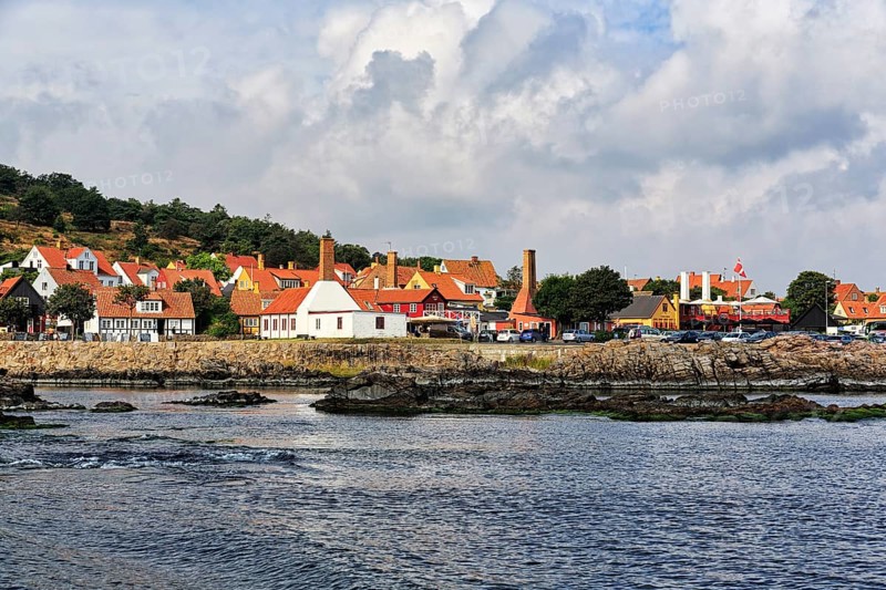 Many old half-timbered houses with red tiled roofs, fish smokehouse chimneys, picturesque port town of Gudhjem on the east coast of the Danish island of Bornholm, Baltic Sea, Denmark