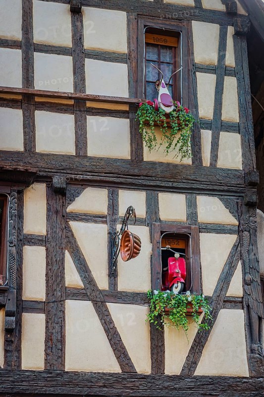 Timber-frame house decorated with vehicles in the historic old town of Riquewihr, Ellsass