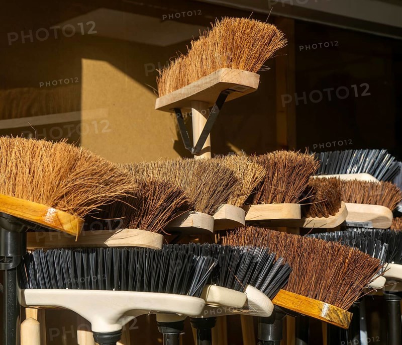 Display of bristled heads of broom brushes outside hardware shop, UK