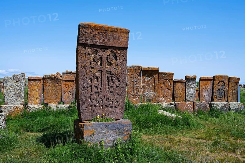 Historic Armenian crossstones stand on a green meadow under a blue sky, crossstones, khachkars, world's largest khachkar field, Noratus cemetery, Noradus, Gegharkunik province, Armenia