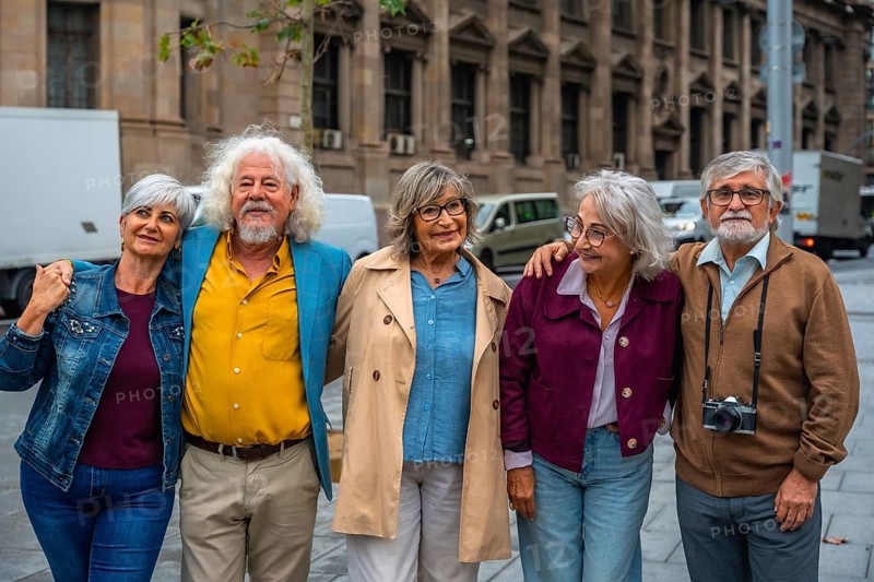 Smiling group of diverse senior friends standing close, showing togetherness and happiness while exploring an urban city during their travel adventure