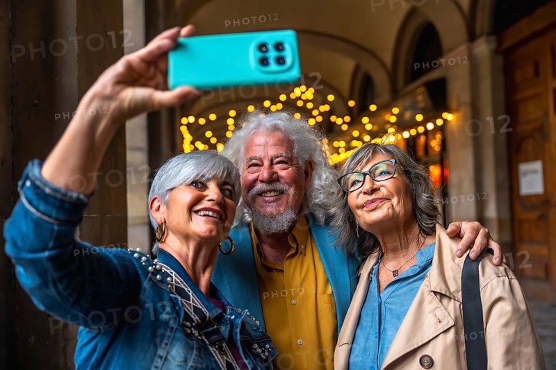 Three happy senior friends enjoying a city trip, smiling and embracing while taking a joyful selfie with a smartphone, capturing a moment of friendship and travel