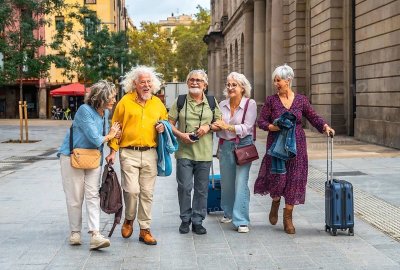 Happy group of five older friends traveling and walking arm in arm through a european city, enjoying their vacation and an active retirement lifestyle