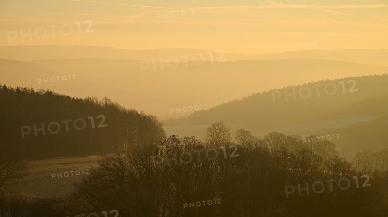 Blurred hills and trees in morning fog with a golden sky at sunrise, Seckmauern, Lützelbach, Maintal, Odenwald, Hesse, Germany