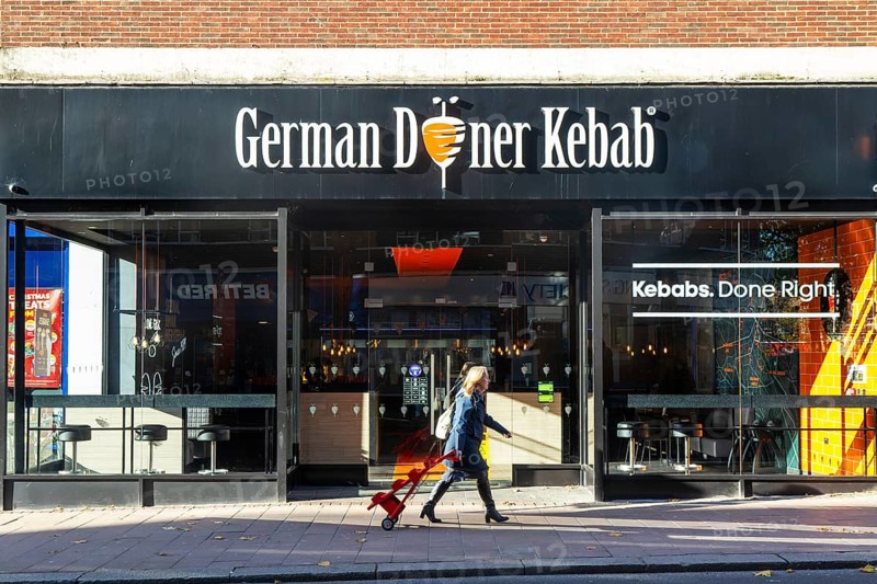 Person passing GDK German Doner Kebab takeaway restaurant in city centre, Exeter, Devon, England, UK