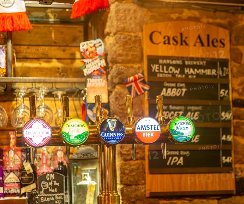 Keg beer taps and labels of different brands inside The Ship pub, Exeter, Devon, England, UK - cask ale menu in background