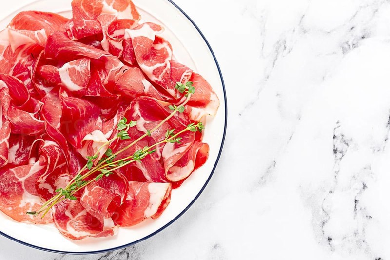 Plate with sliced cured meat, pork neck, prosciutto coppa, Italian delicacy