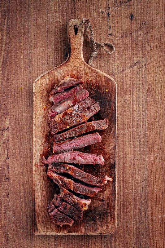 Medium rare, sliced rib eye steak, grilled cowboy steak, on a chopping board, close-up, homemade, top view, no people
