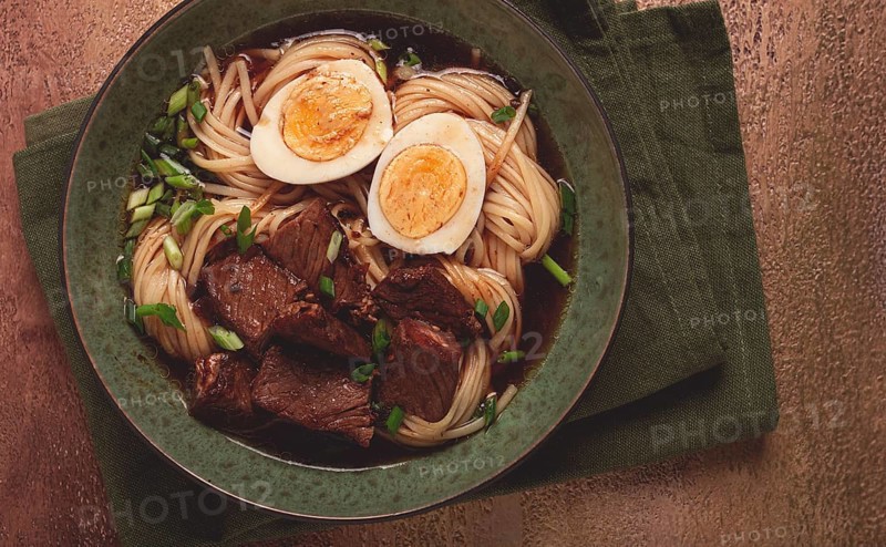 Asian noodles in broth, with beef and egg, top view, close-up, no people