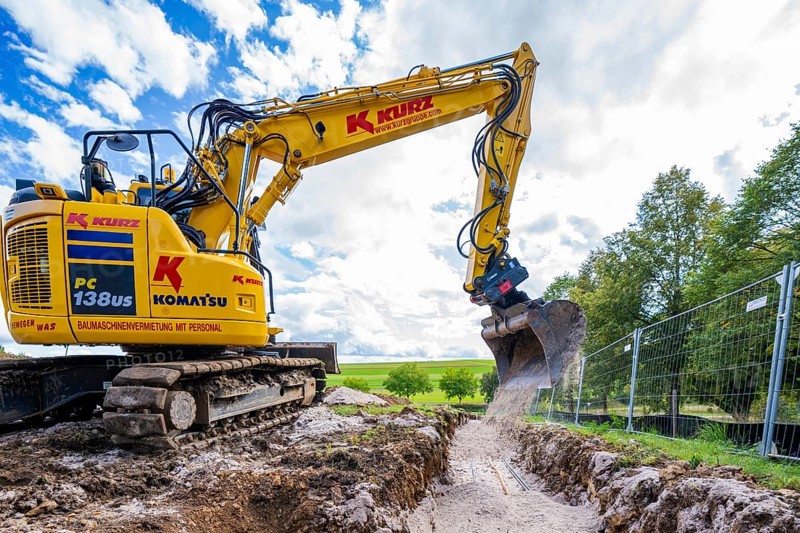 A yellow excavator digging on a construction site under a cloudy sky, Bau PV Freifaechenanlage, Weil der Stadt, Germany