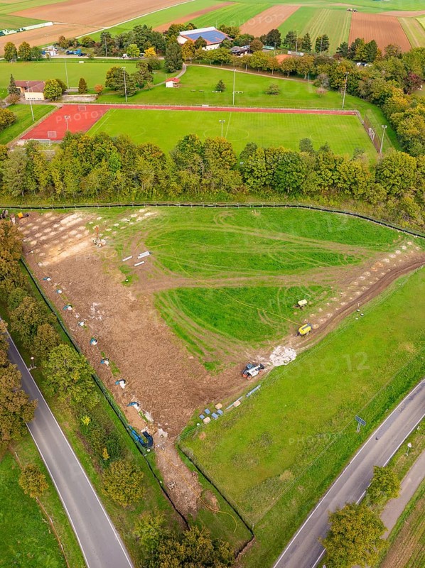 Aerial view of a green landscape with tennis court and surrounding trees, PV Freifaechenanlage construction, Weil der Stadt, Germany