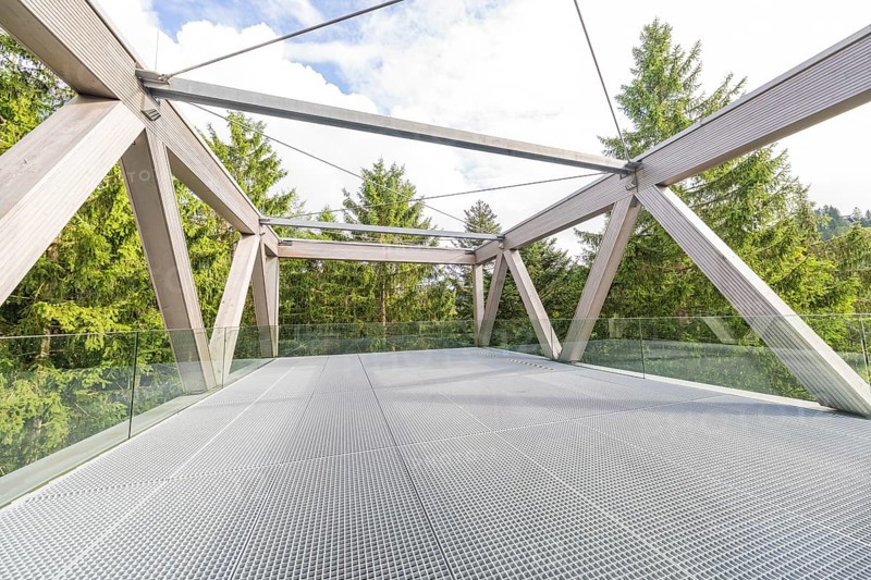 Viewing platform with metal mesh floor and wooden structure, surrounded by green trees and sky, Ruhestein National Park Center, Black Forest, Baiersbronn, Germany