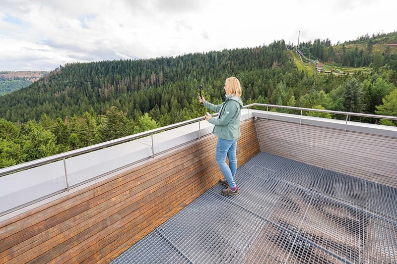 Individual taking photos of an elevated platform with a view of wooded hills, Ruhestein National Park Center, Black Forest, Baiersbronn, Germany