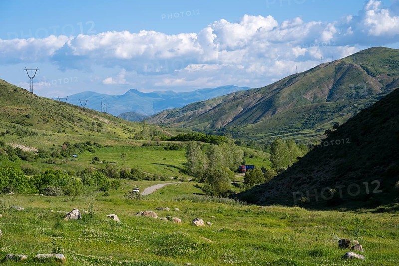 Valley with green landscape, power lines, surrounded by mountains and under a cloudy sky, landscape from south towards Vardenyats Pass or Selim Pass, Vayots Dzor Province, Armenia